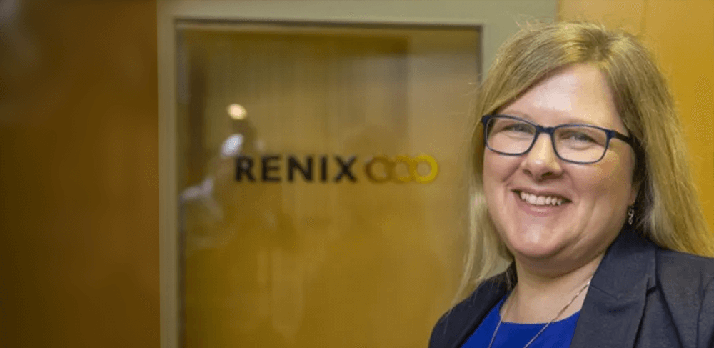 Christina Haas standing in front of the Renix Logo on Glass behind her.